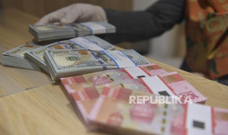 Karyawan menghitung uang rupiah dan dolar AS di Bank Mandiri Syariah, Jakarta, Senin (20/4). Rupiah diprediksi akan stabil dan menguat ke arah Rp 15.000 per dolar AS. 