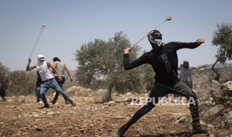 Demonstran Palestina menggunakan ketapel untuk melemparkan batu selama protes terhadap pos terdepan pemukiman Yahudi Tepi Barat Eviatar yang dengan cepat didirikan bulan lalu, di desa Palestina Beita, dekat kota Nablus, Tepi Barat, Jumat, 25 Juni 2021. 