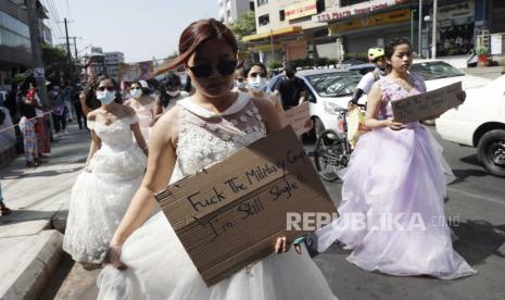  Wanita mengenakan gaun pesta memegang spanduk saat mereka berbaris selama protes menentang kudeta militer, di Yangon, Myanmar, 10 Februari 2021. Orang-orang terus berdemonstrasi di seluruh negeri meskipun ada perintah yang melarang pertemuan massal dan laporan peningkatan penggunaan kekuatan oleh polisi terhadap pengunjuk rasa anti-kudeta. 