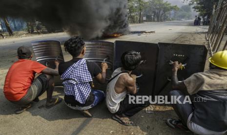 Demonstran berlindung di balik perisai logam selama protes terhadap kudeta militer di Kotapraja Hlaingthaya (Hlaing Tharyar), pinggiran Yangon, Myanmar, Ahad (14/3).. Protes anti-kudeta terus berlanjut meskipun tindakan keras yang intensif terhadap demonstran oleh pasukan keamanan.