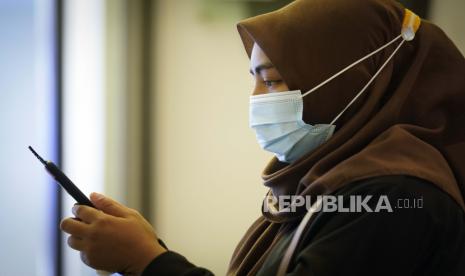 Seorang wanita mengenakan masker untuk membantu mengekang penyebaran virus corona.