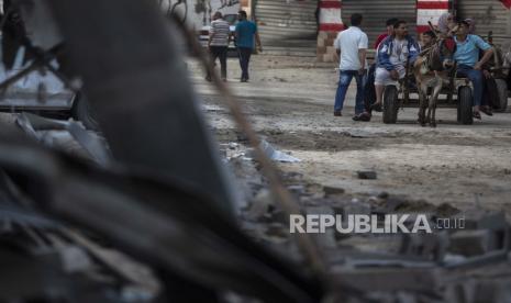 Warga Palestina di atas kereta keledai melewati kehancuran yang disebabkan oleh serangan udara Israel di kamp pengungsi Jabaliya, Jalur Gaza utara, Kamis, 20 Mei 2021.