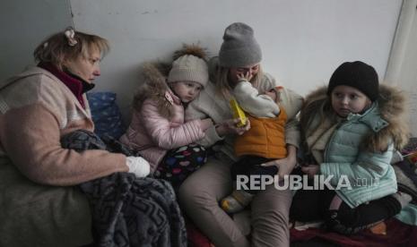  Wanita dan anak-anak duduk di lantai koridor di sebuah rumah sakit di Mariupol, Ukraina timur Jumat, 11 Maret 2022.