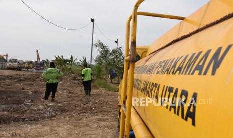 Pekerja dibantu alat berat menyiapkan lahan untuk Tempat Pemakaman Umum (TPU) Rorotan,  di Jakarta Utara.