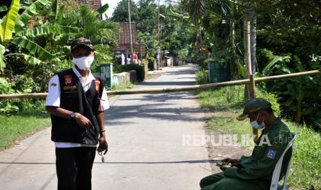 Satgas Covid-19 berjaga saat karantina wilayah di Pedukuhan Ngino XII, Seyegan, Sleman, Yogyakarta, Jumat (18/6). Sebanyak 250 KK dari empat RT harus menjalani karantina wilayah usai ada warga positif Covid-19 pascaziarah. Satgas Covid-19 Kalurahan Margoagung berjaga di gerbang masuk desa untuk melarang warga keluar lokasi.