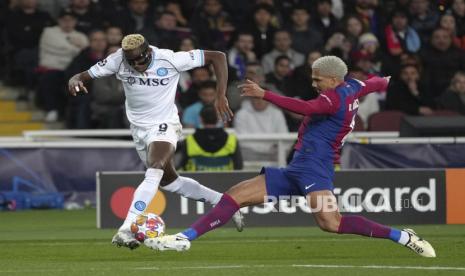 Napoli Victor Osimhen, kiri, ditantang Barcelona Ronald Araujo saat laga leg kedua Liga Champions babak 16 besar antara Barcelona dan SSC Napoli di stadion Olympic Lluis Companys di Barcelona, Spanyol,  Rabu (13/3/2024) dini hari WIB.