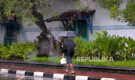 Warga beraktivitas menggunakan payung saat hujan di kawasan Ngabean, Yogyakarta.