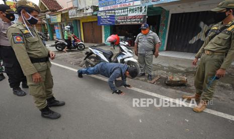 Personel gabungan Polri dan Satuan Polisi Pamong Praja memberi hukuman kepada warga yang terjaring Operasi Pendisiplinan Protokol Kesehatan di Pasar Induk Rau, Serang, Banten, Rabu (13/1/2021). Operasi tersebut digelar untuk mendisiplinkan warga dalam mematuhi ketentuan protokol kesehatan selama Pemberlakuan Pembatasan Kegiatan Masyarakat (PPKM) tanggal 11-25 Januari 2021 guna menekan penyebaran COVID-19. 