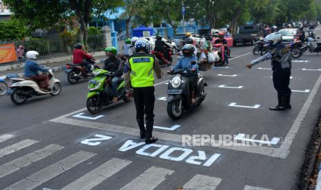 Petugas Dinas Perhubungan dan polisi Satuan Lalu Lintas (Satlantas) mengarahkan pengendara motor berhenti di belakang garis untuk menjaga jarak antarpengendara di Jalan Wahid Hasyim Kabupaten Jombang, Jawa Timur, Rabu (15/7/2020). Kepolisian dan Dinas Perhubungan setempat membuat garis tersebut untuk membatasi jarak antarpengendara guna mencegah penyebaran COVID-19. ANTARA FOTO/Syaiful Arif/aww. 