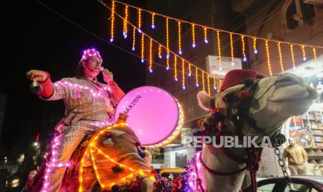 Mohammed El-Dahshan, seorang Mesaharati, berkeliling dengan balutan lampu LED untuk membangunkan sahur di kota Delta, Kairo, Mesir, Kamis (14/3/2024). 