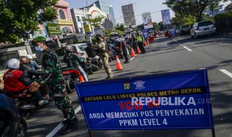 Petugas gabungan mengatur lalu lintas saat dilakukan penyekatan di Jalan Raya Margonda, Depok . 