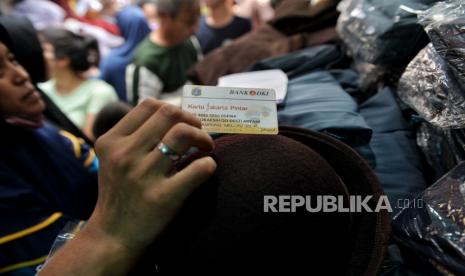 Calon pembeli melakukan transaksi menggunakan kartu jakarta pintar (KJP) saat membeli seragam sekolah di Pasar Mester Jatinegara. Anggota DPRD sebut ada penerima KJP pakai uang malah buat beli rokok.