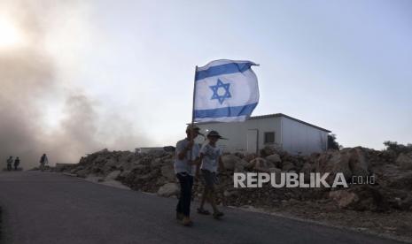 Pemuda Israel membawa bendera di pos terdepan Eviatar dekat kota Nablus di Tepi Barat utara, Senin, 21 Juni 2021.