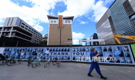 Pejalan kaki dengan memakai masker wajah melewati pameran fotografi luar ruangan tentang petugas kesehatan di Melbourne, Australia, Selasa (22/9). Pameran fotografi ini bertujuan untuk memberi penghargaan kepada orang-orang yang bekerja di Parkville Biomedical Precinct, yang merupakan rumah bagi beberapa peneliti medis, dokter, dan akademisi terkemuka dunia selama pandemi Covid-19. EPA-EFE/JAMES ROSS AUSTRALIA AND NEW ZEALAND OUT