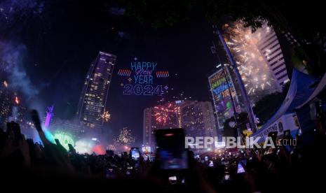 Warga menyaksikan atraksi konfigurasi drone dan pesta kembang api saat pergantian tahun 2023 menuju 2024 di kawasan Bundaran Hotel Indonesia, Jakarta, Senin (1/1/2024) dini hari. Dalam rangka menyambut perayaan Tahun Baru 2024, Pemerintah Provinsi (Pemprov) DKI Jakarta menghadirkan sejumlah atraksi di antaranya 3D video mapping, konfigurasi drone, water mist, Jakarnaval, serta belasan panggung hiburan di sepanjang Jalan Sudirman-Thamrin.