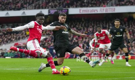 Pemain Arsenal Bukayo Saka (kiri) melakukan tembakan ke gawang di depan pemain Bournemouth Lloyd Kelly pada pertandingan sepak bola Liga Premier Inggris antara Arsenal dan Bournemouth di stadion Emirates di London, Inggris, Sabtu (4/3/2023).