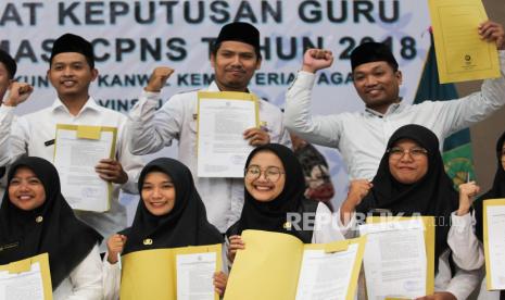 Sejumlah guru berpose dengan menunjukkan SK Guru yang didapat saat Pembinaan dan Penyerahan Surat Keputusan (SK) Guru Formasi CPNS 2018 di Surabaya, Jawa Timur, Sabtu (30/12/2023). Kantor Wilayah Kementerian Agama Provinsi Jawa Timur menyerahkan SK Guru kepada 652 guru Formasi CPNS 2018. 