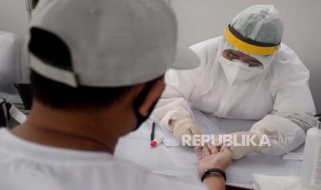 Petugas medis mengambil sampel darah warga saat mengikuti rapid test Covid-19.