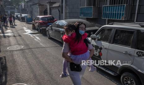 Seorang wanita berjalan dengan seorang gadis ke taman kanak-kanak pada Hari Anak Internasional, di lingkungan Hutong, Beijing, China, 1 Juni 2021. 