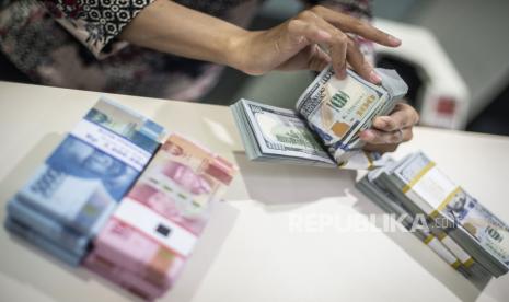 Karyawan menghitung uang dolar AS dan rupiah. ANTARA FOTO/Aprillio Akbar/wsj.