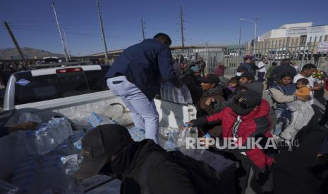 Relawan membagikan air kepada para migran yang berdiri di luar pusat penahanan imigrasi tempat kebakaran menewaskan puluhan orang, di Ciudad Juarez, Meksiko, Selasa, 28 Maret 2023.  Presiden Meksiko Andres Manuel Lopez Obrador mengunjungi kota perbatasan tempat 39 migran meninggal dalam kebakaran di sebuah pusat penahanan migran. Dia mengungkapkan rasa sakitnya atas bencana tersebut dan menyalahkan Amerika Serikat (AS) lebih memilih Ukraina.