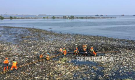 Sejumlah pekerja membersihkan sampah plastik dari pantai yang tercemar di Marunda,  Jakarta Utara, Jumat (2/6/2023).