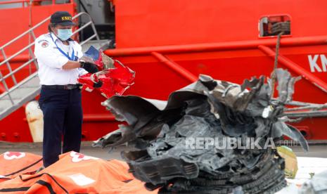 Anggota Komite Nasional Keselamatan Transportasi memeriksa bagian dari mesin Sriwijaya Air penerbangan SJ182 yang ditemukan di perairan Jakarta, di pelabuhan Tanjung Priok di Jakarta, Indonesia, 12 Januari 2021. Kontak dengan penerbangan Sriwijaya Air SJ182 hilang pada 09 Januari 2021 tak lama setelah pesawat lepas landas dari Bandara Internasional Jakarta saat dalam perjalanan menuju Pontianak di provinsi Kalimantan Barat. Pesawat itu jatuh ke laut di lepas pantai Jakarta.