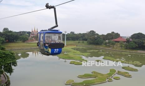 Pengunjung menikmati kereta gantung saat berwisata di Taman Mini Indonesia Indah (TMII), Jakarta, Selasa (18/6/2024). 