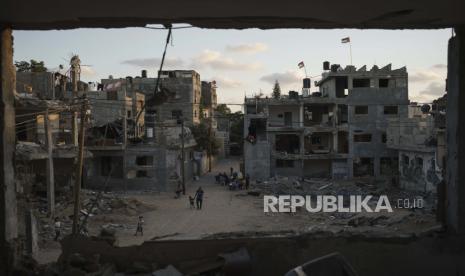 Bendera Palestina berkibar di atas gedung-gedung yang rusak berat akibat serangan udara selama perang 11 hari antara penguasa Hamas Gaza dan Israel, Sabtu, 5 Juni 2021, di Beit Hanoun, Jalur Gaza.