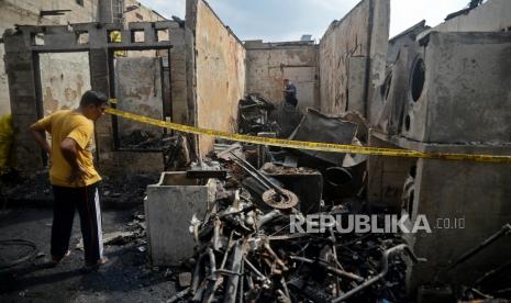 Warga melihat puing-puing rumah yang hangus terbakar di kawasan Kali Pasir, Cikini, Jakarta, Sabtu (18/12). Kebakaran yang terjadi di pemukiman padat penduduk tersebut menghanguskan puluhan unit rumah warga.