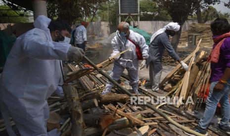 Anggota keluarga mengumpulkan kayu bakar untuk kremasi di tempat kremasi di New Delhi, India, Kamis (29/4). Delhi melaporkan 25.986 kasus baru, 368 kematian dalam 24 jam terakhir dan terus berjuang dengan pasokan oksigen.