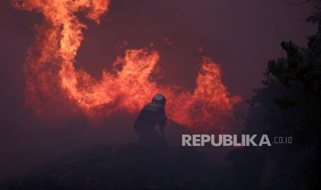 Pemadam berusaha memadamkan api saat terjadi kebakaran di Athena utara, Senin (12/8/2024). 