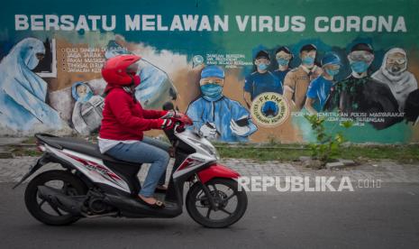 Warga melintas di depan mural bertema Bersatu Melawan COVID-19 di Kampung Kemlayan, Serengan, Solo, Jawa Tengah, Senin (20/4/2020). Mural tersebut sebagai bentuk dukungan dan apresiasi kepada tenaga medis yang bertugas di garis terdepan dalam penanggulangan COVID-19 serta mengajak masyarakat untuk mengikuti imbauan Pemerintah guna meminimalisir penyebaran COVID-19