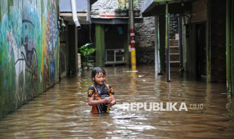 Seorang bermain banjir saat melanda kawasan Kebon Pala, Kampung Melayu, Jakarta, Kamis (30/1/2025).