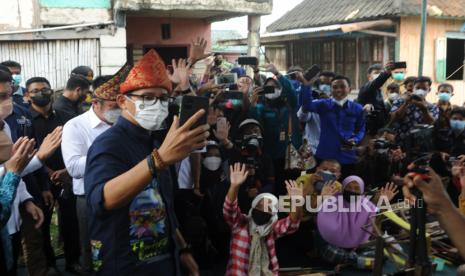 Menteri Pariwisata dan Ekonomi Kreatif Sandiaga Uno  (kiri) merekam promosi wisata melalui gawai bersama para pengrajin songket dan warga pada kunjungan ke Desa Wisata Burai Kabupaten Ogan Ilir, Sumsel, Kamis (30/9/2021). Kunjungan Menparekraf ke Desa Wisata Burai ini merupakan salah satu dari 50 kunjungan desa wisata terbaik untuk mewujudkan desa wisata berkelas dunia, berdaya saing, dan berkelanjutan. 