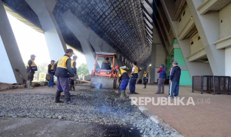 Petugas Dinas Pekerjaan Umum (DPU) memperbaiki jalan di halaman Stadion Gelora Bandung Lautan Api (GBLA), Kota Bandung, Jumat (10/6). Berbagai elemen masyarakat dari berbagai komunitas dan para petugas terkait bergotong-royong membersihkan dan memperbaiki sejumlah fasilitas GBLA. kegiatan tersebut merupakan persiapan jelang turnamen pramusim Piala Presiden 2022.