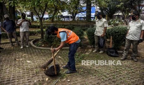 Pelanggar aturan penggunaan masker membersihkan area publik di kawasan Taman Alun-alun Kota Cimahi, Jalan Raya Barat, Kota Cimahi, Rabu (12/8). Pemerintah Kota Cimahi menerapkan sanksi denda sebesar Rp150 ribu serta sanksi sosial yakni kewajiban membersihkan area publik bagi warga yang tidak menggunakan masker di tempat umum. Foto: Abdan Syakura/Republika