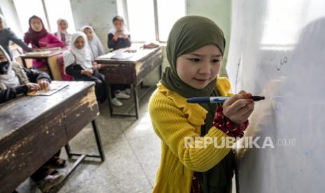 Seorang siswi sekolah Afghanistan menulis di papan tulis saat siswi menghadiri kelas mereka pada hari pertama tahun ajaran baru, di Kabul, Sabtu (25/3/2023). Tahun pendidikan baru Afghanistan dimulai di Afghanistan, sementara sekolah menengah tetap ditutup untuk anak perempuan selama tahun kedua setelah Taliban kembali berkuasa pada 2021.