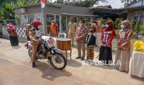 Bupati Batang Wihaji (kedua kiri) mengendarai sepeda motor menghadiri acara khitan dengan sistem drive thru di Desa Tambahrejo, Bandar, Kabupaten Batang, Jawa Tengah, Selasa (3/8/2021). Pemerintah setempat mengizinkan warga Kabupaten Batang mengadakan acara hajatan secara drive thru atau sistem layanan tanpa turun saat pandemi COVID-19 untuk mengurangi laju penyebaran virus COVID-19. 