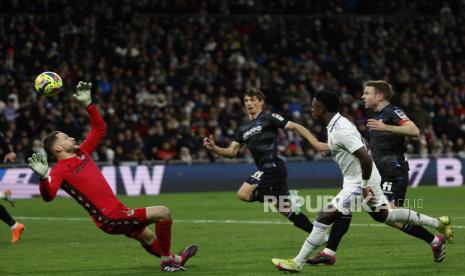 Striker Real Madrid Brasil Vinicius Jr (2-R) beraksi melawan kiper Real Sociedad Alex Remiro (Kiri) selama pertandingan sepak bola LaLiga Spanyol antara Real Madrid dan Real Sociedad, di Madrid, Spanyol, Senin (30/1/2023).