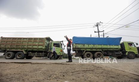 Petugas Dishub menghentikan truk yang akan melintas di Jalan Sudamanik, Parung Panjang, Kabupaten Bogor, Jawa Barat, Senin (20/11/2023). Kondisi jalan yang rusak serta berlubang dan keberadaan truk muatan tambang yang beroperasi pada jam yang belum ditentukan tersebut dapat membahayakan keselamatan pengendara lain.