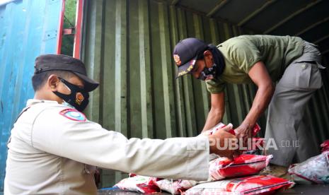 Petugas menurunkan beras saat penyaluran bantuan beras PPKM 2021 di Kalurahan Panembahan, Yogyakarta, Jumat (23/7). Sebanyak 221 paket bantuan berisi 10 kilogram beras disalurkan oleh PT Pos Indonesia ke masyarakat.