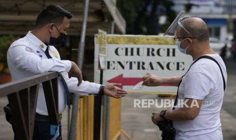 Seorang pria menunjukkan kartu vaksinnya untuk memasuki Gereja Santo Domingo di kota Quezon, Filipina saat kegiatan keagamaan dibuka kembali dengan pembatasan kesehatan pada Kamis, 16 September 2021.