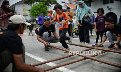 Anak memainkan permainan tradisional rangku alu pada gelaran Festival Permainan Tradisional Anak di kawasan Kota Tua Jakarta, Ahad (13/11/2022). Festival tersebut menyediakan sembilan permainan seperti gasing, engklek, congklak, lompat tali, rangku alu, bola bekel, kapal otok-otok, petak umpet dan petak jongkok. Gelaran tersebut bertujuan untuk  menjaga kelestarian permainan tradisional anak.