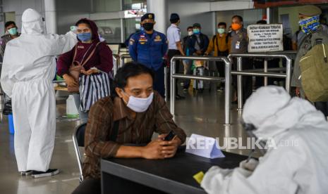 Petugas kesehatan memeriksa suhu tubuh dan mendata penumpang yang baru saja tiba di terminal kedatangan Bandar Udara Mutiara Sis Aljufri, Palu, Sulawesi Tengah, Selasa (14/4/2020). Pemerintah Kota Palu memperketat arus orang masuk yang menggunakan pesawat udara ke kota itu dengan memeriksa dan mendata setiap penumpang yang baru tiba untuk mencegah makin masifnya penularan virus corona di wilayah itu