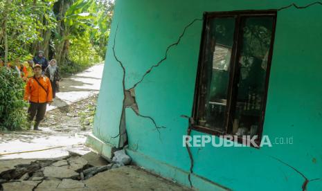 Petugas mengamati tembok rumah yang retak akibat pergerakan tanah di Jatisari, Bojongpicung, Kabupaten Cianjur, Jawa Barat, Sabtu (27/4/2024). 