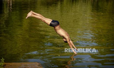 Anak laki-laki berenang di sebuah danau di Bucharest, Rumania, Selasa (9/7/2024). 