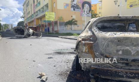 Mobil hangus terlihat di jalan Le Gosier, pulau Guadeloupe, Minggu, 21 November 2021. Pihak berwenang Prancis mengirim pasukan khusus polisi ke pulau Karibia Guadeloupe, wilayah seberang laut Prancis, saat protes atas pembatasan COVID-19 meletus. 