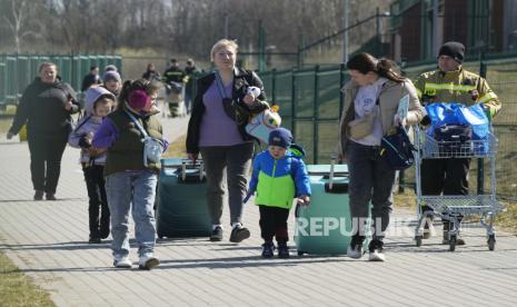  Pengungsi berjalan di perbatasan di Medyka, Polandia tenggara, setelah melarikan diri dari perang dari negara tetangga Ukraina, Ahad, 27 Maret 2022.