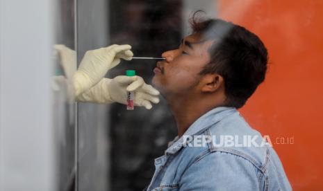  Petugas kesehatan dengan pakaian hazmat mengumpulkan sampel spesimen melalui dinding plexiglass selama tes usap Covid-19 di Medan, Sumatera Utara, Indonesia, 25 November 2020. Menurut angka terbaru, Indonesia telah mencatat lebih dari setengah juta kasus COVID-19 sejak awal pandemi.